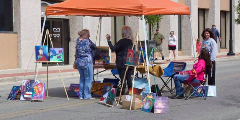 A vendor selling paintings at Art and Stroll