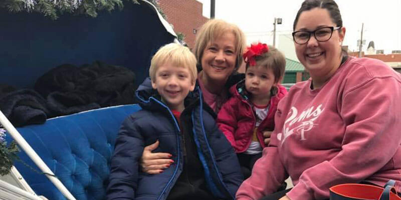 A smiling family on the Horse and carriage at Holiday Traditions