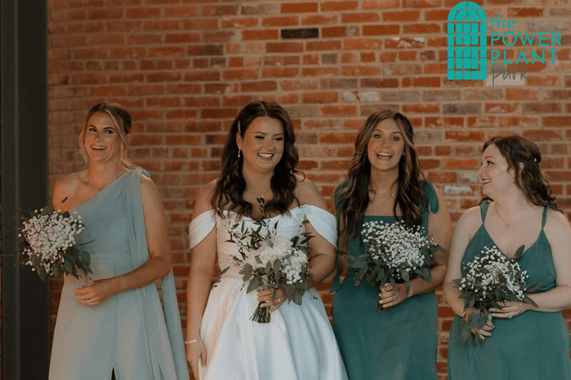 Bride and Bridesmaids smiling for a picture holding flowers.